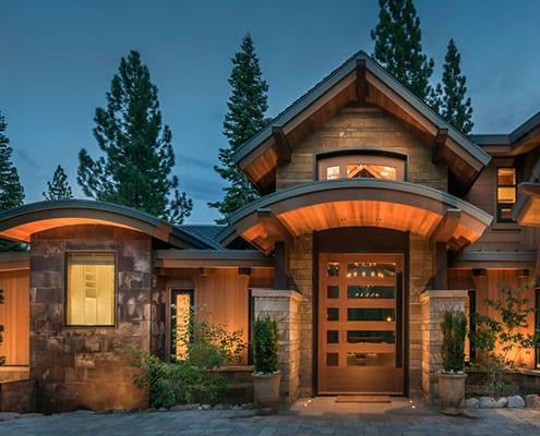 Wooden pivot door featured in exterior night view of modern residence