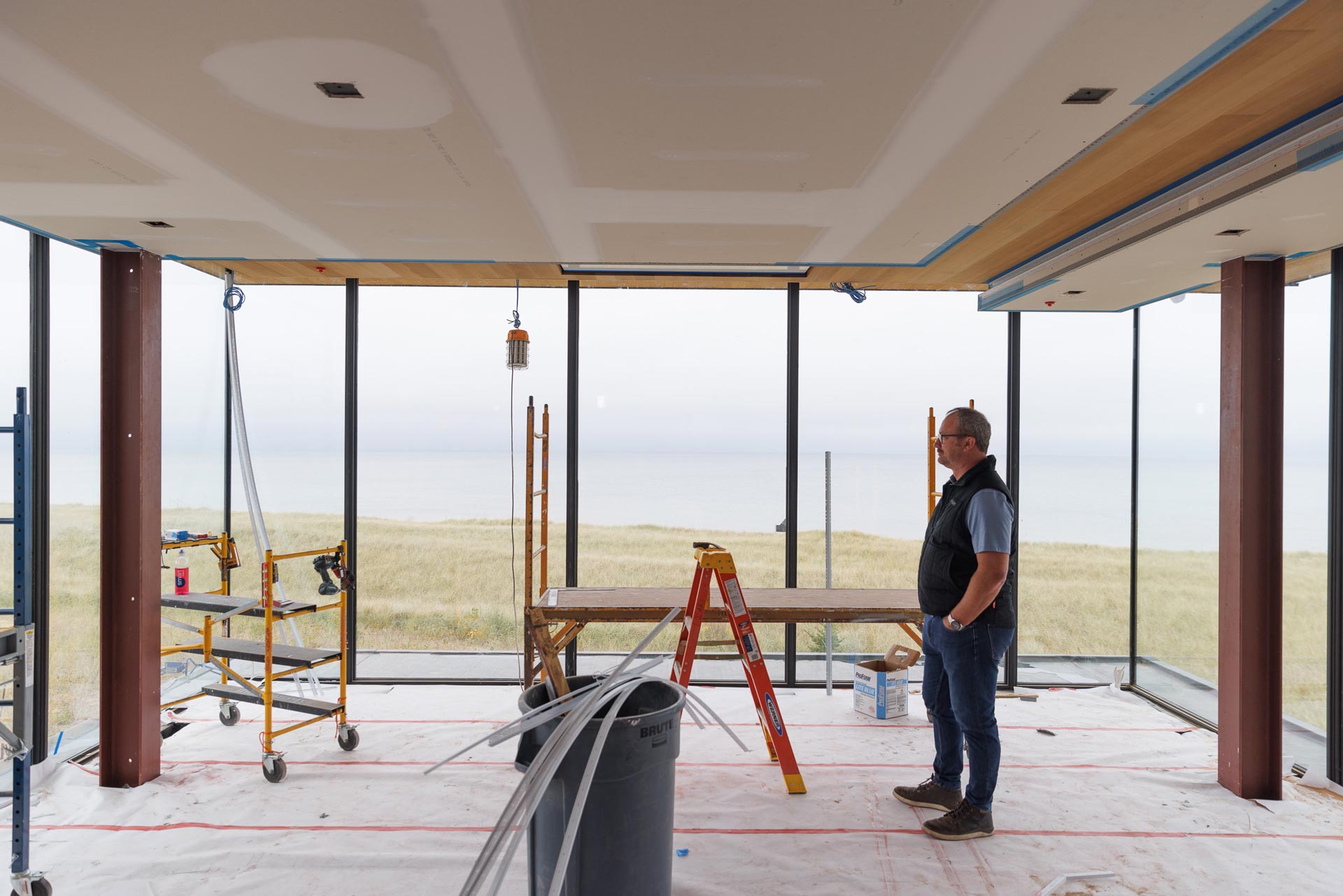 man stands in room being built surrounded by floor to ceiling window walls in Northshore Residence